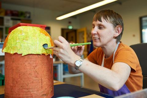 Mitarbeiterin fertigt eine Schale aus Pappmachee