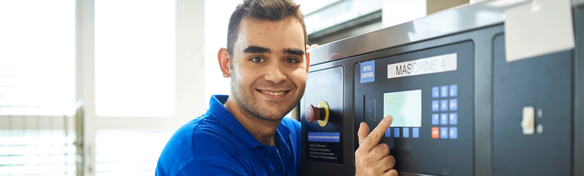 Mitarbeiter der Wäscherei an der Bedienungseinheit der Waschmaschine