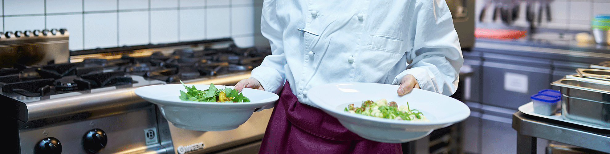 Mitarbeiterin bringt zwei Teller mit Salat aus der Küche