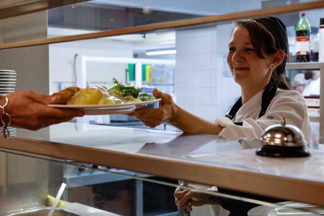 Mitarbeiterin bei der Essenausgabe in der Mosaik-Kantine Konzerthaus, Juni 2024