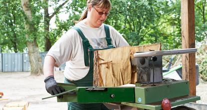 Mitarbeiterin der Garten- und Landschaftspflege arbeitet an der Holzspaltmaschine