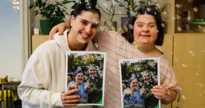 Zwei Beschäftigte der Mosaik-Werkstatt für Menschen mit Behinderungen halten das Mosaik Magazin hoch - Die Ausgabe ist zum 60.  Jubiläum von Mosaik erschienen