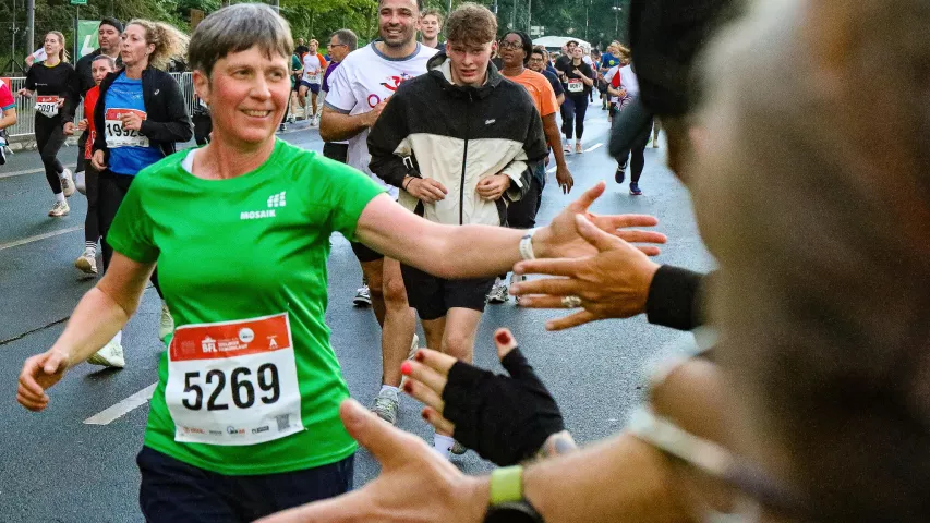 Mosaik-Läuferin beim Berliner Firmenlauf beim Abklatschen mit dem Publikum