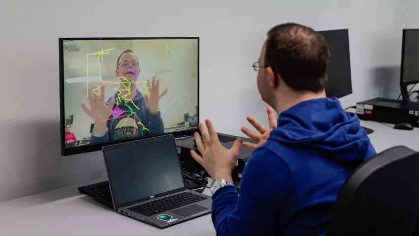 BFB-Teilnehmer sitzt am Laptop und schafft mit seinen Händen digitale Bilder