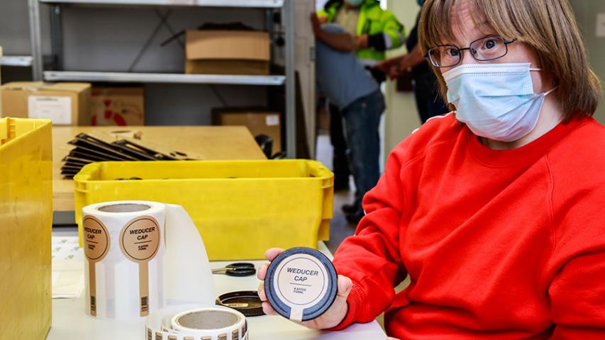 Mitarbeiterin der Mosaik-Betriebsstätte Kreuzberg beklebt einen Kaffeedeckel