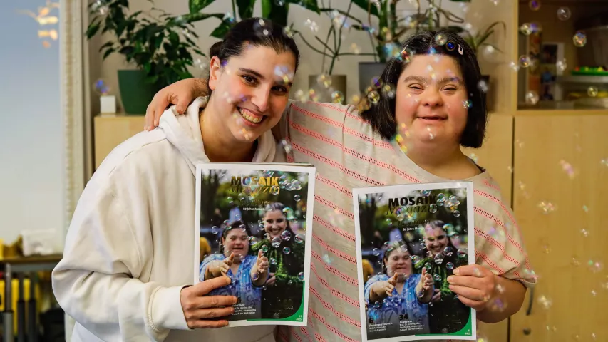 Zwei Beschäftigte der Mosaik-Werkstatt für Menschen mit Behinderungen halten das aktuelle Mosaik Magazin hoch