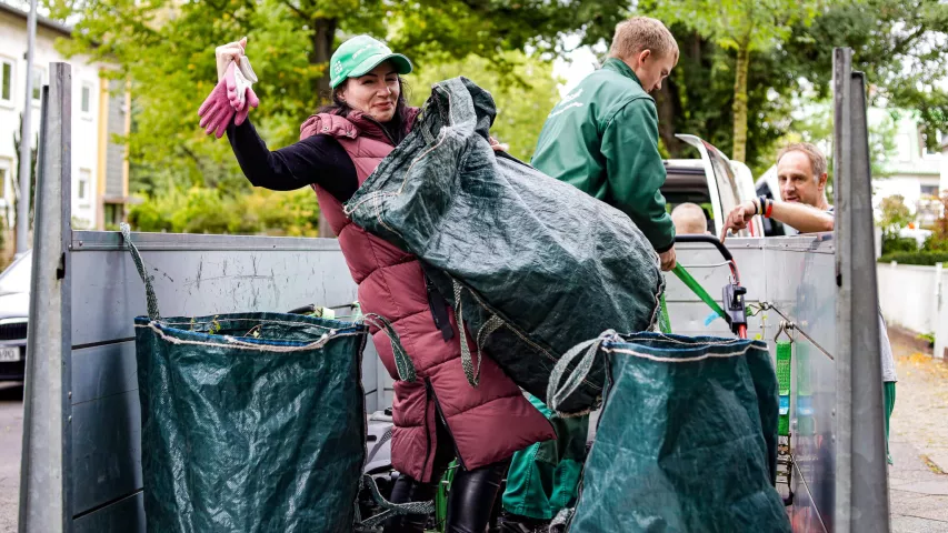Mit Freude dabei - Schichtwechslerin unterstützt unser Team der Garten- und Landschaftspflege, hier beim Einladen der Pflanzenreste auf die Ladefläche eines Transporters